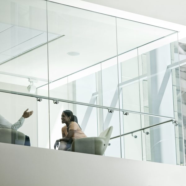 Businessman and woman standing behind a conference room window ina large business center.