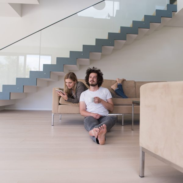 Young couple relaxing at luxurious home with tablet computers reading in the living room on the sofa couch.